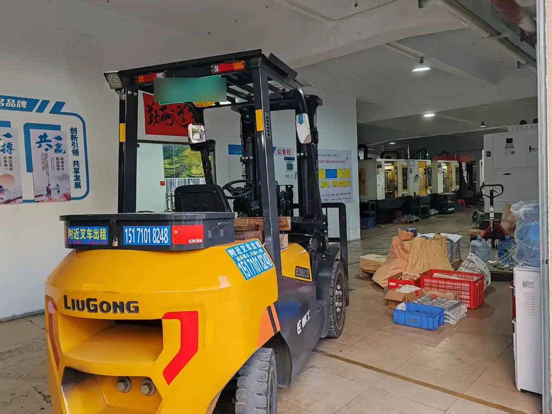 A forklift moving material in the cleared bay, with the running production line in the background